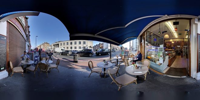 The cafe frontage and its pavement tables under the blue awning.