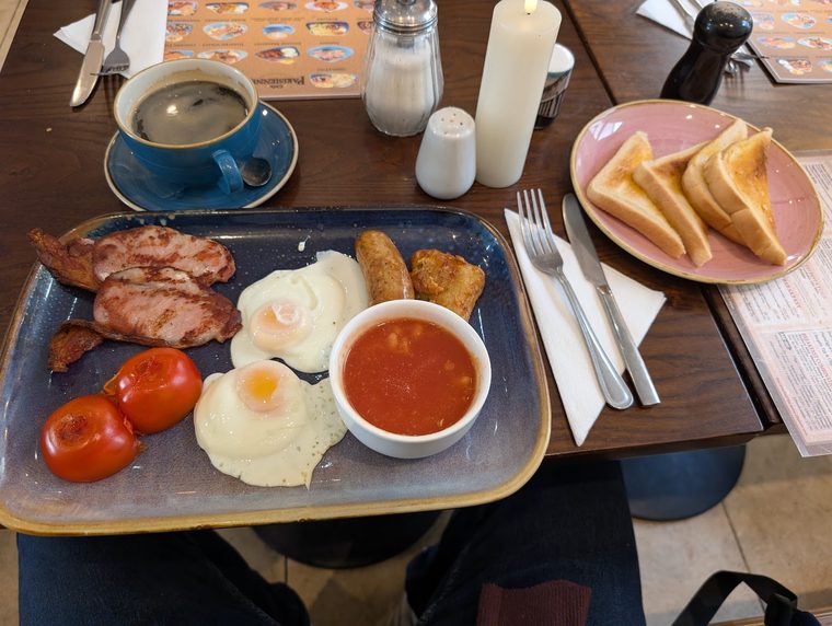 Cooked breakfast with a hash brown, served with a cappuccino and toast.