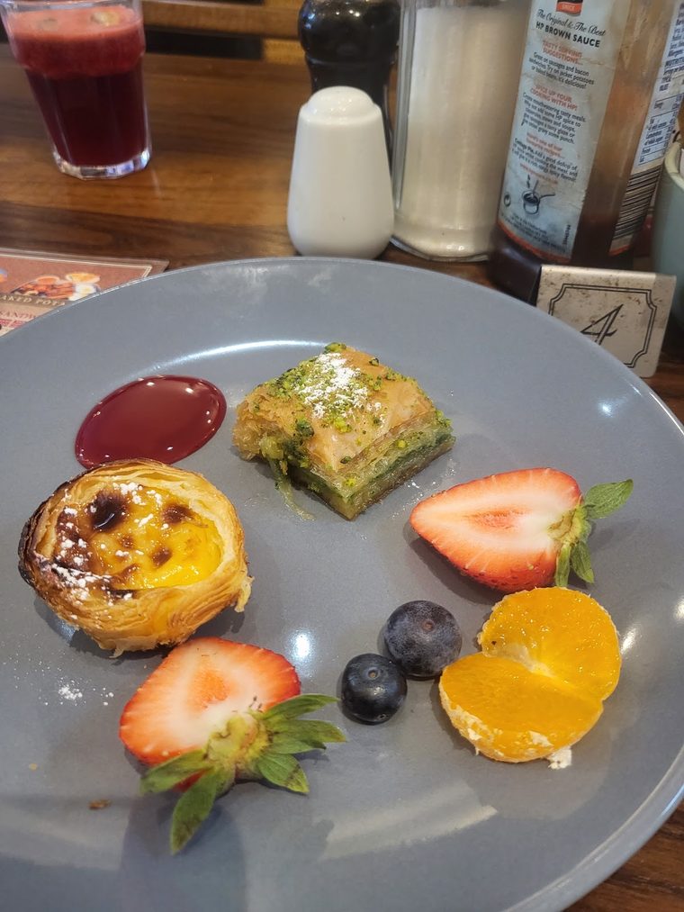 Baklava, a Portuguese custard tart and a fresh fruit tart on one plate.